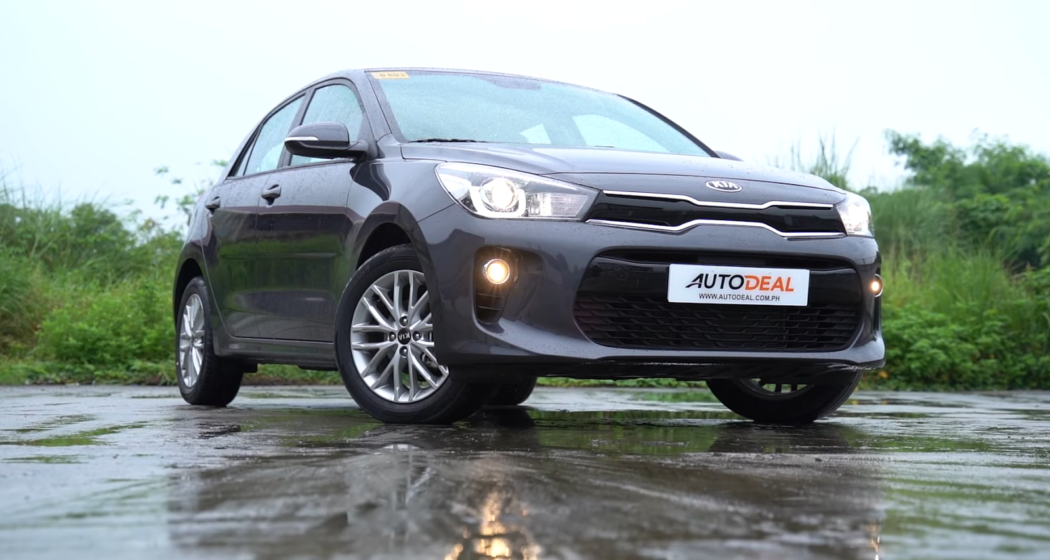 gray car kia hatchback and wet asphalt road with the trees behind