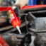 Gloved hand applying grease to a car engine