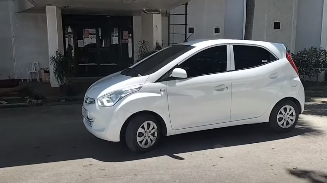 Side view of white Hyundai Eon in front of a building