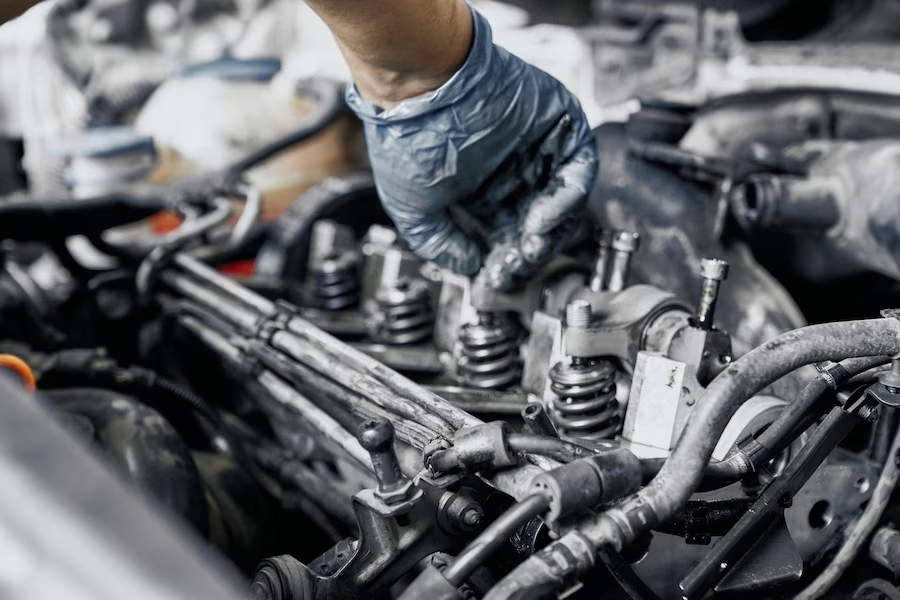 Hand in gloves repairing a car engine