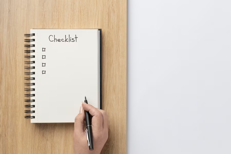 A hand holding a pen over a notebook displaying a checklist