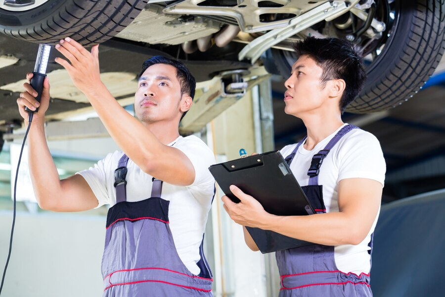 Two men working underneath a car chassis