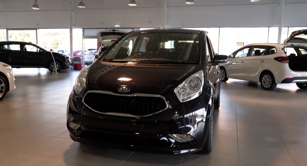 Kia Venga in car salon, white and black cars behind