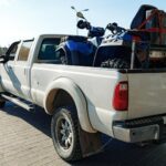 White Pickup Car Loaded With ATV Near Gas Station