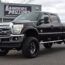 A big black Ford car is parked on the street